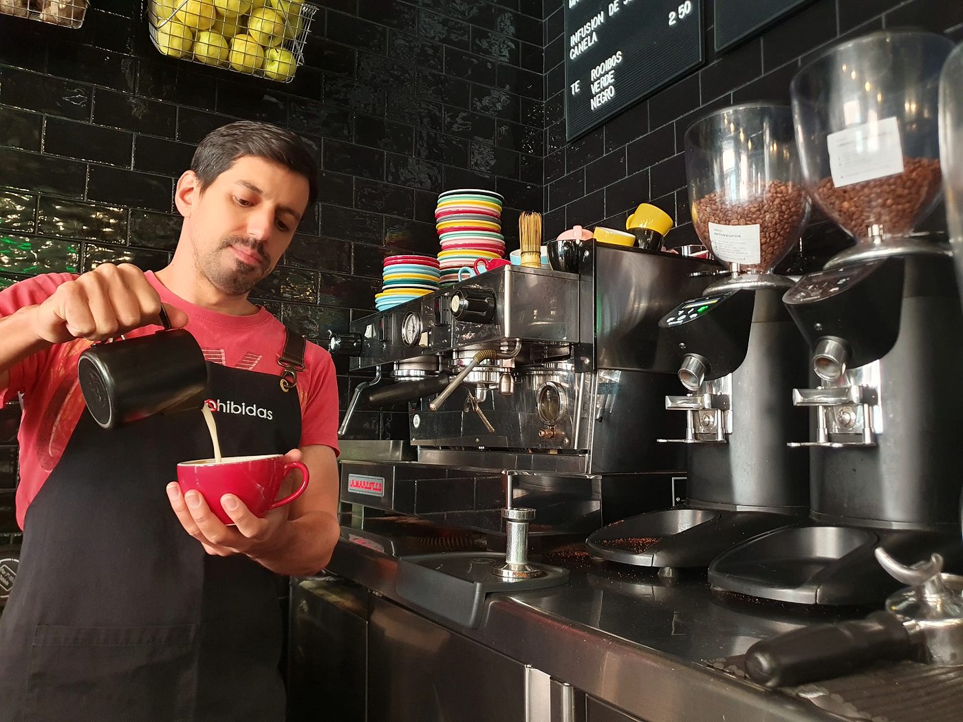 Barista de Frutas Prohibidas vertiendo leche vegetal para hacer latte art junto a la máquina de espresso