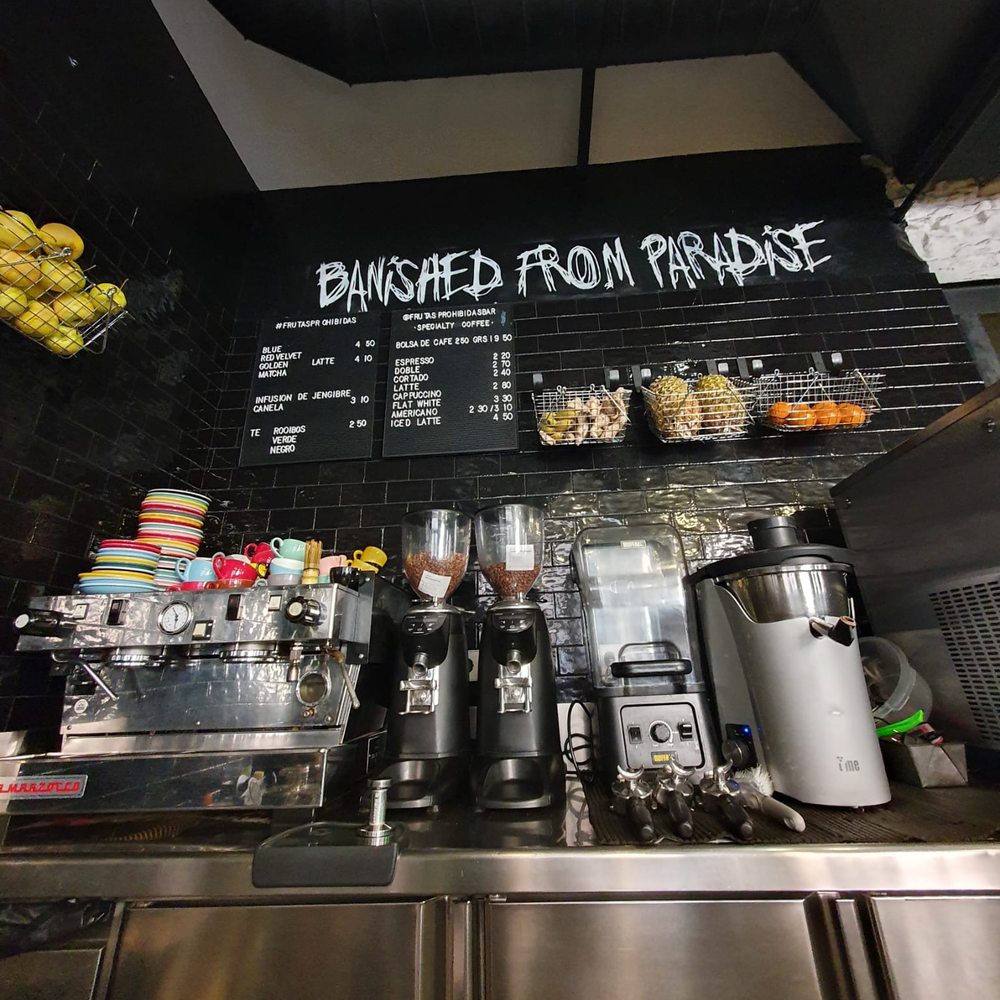 Barra de Frutas Prohibidas con la máquina de espresso, los molinos y la pizarra de precios