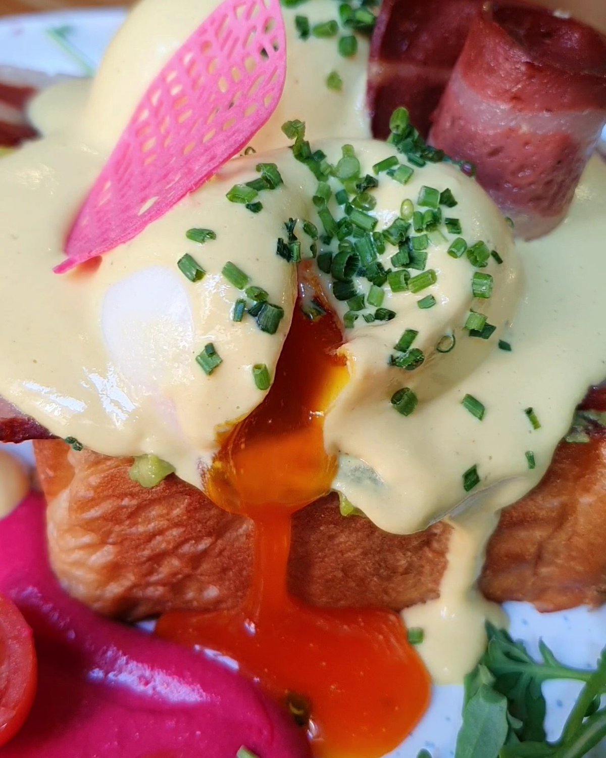 Huevos Benedict veganos de Frutas Prohibidas: la yema del huevo vegetal cayendo sobre el brioche, con holandesa de anacardos, cebollino y bacón de setas