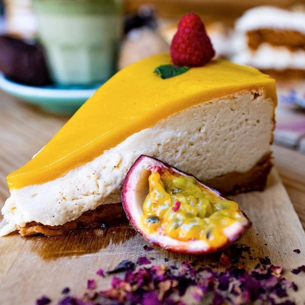 Porción de cheesecake de maracuyá del obrador, con la fruta fresca al lado