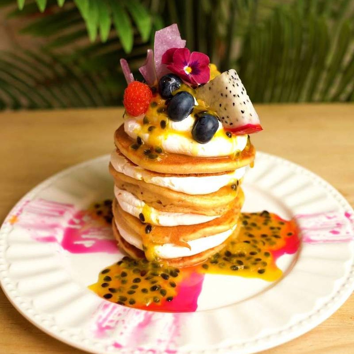 Torre de pancakes veganos con chantillí, salsa de maracuyá, arándanos, pitaya y una flor comestible
