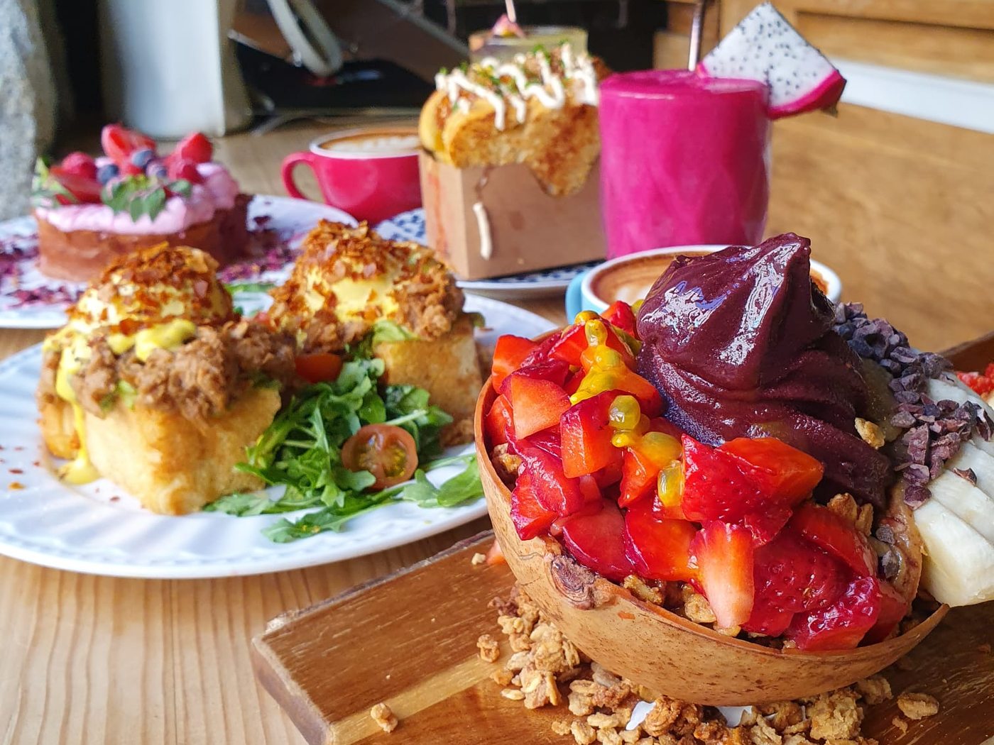 Mesa de Frutas Prohibidas con huevos Benedict, açaí bowl en coco, smoothie de pitaya y tartas